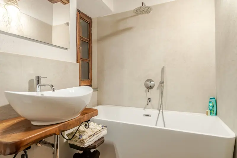 Bagno con vasca e lavabo su mensola in legno