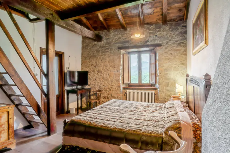 Camera con letto in ferro e travi a vista